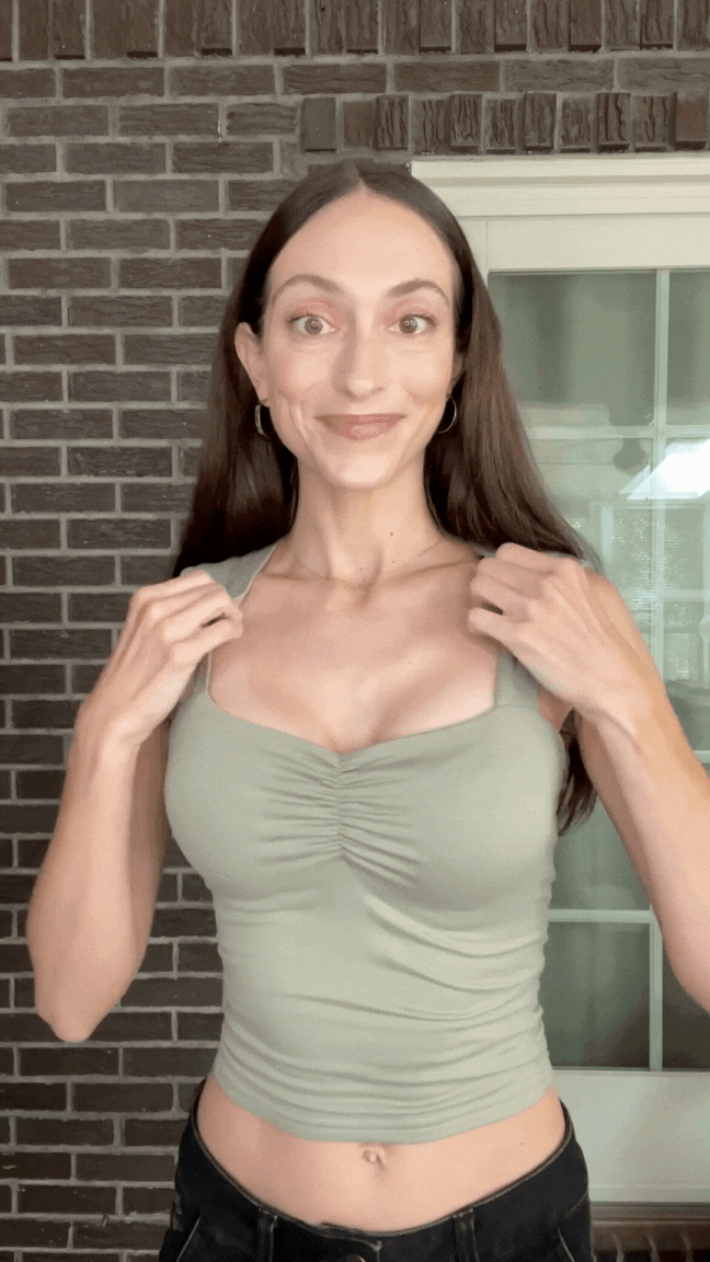 Woman smiling while wearing a black sports bra with Honeycloudz bra pads inserted.