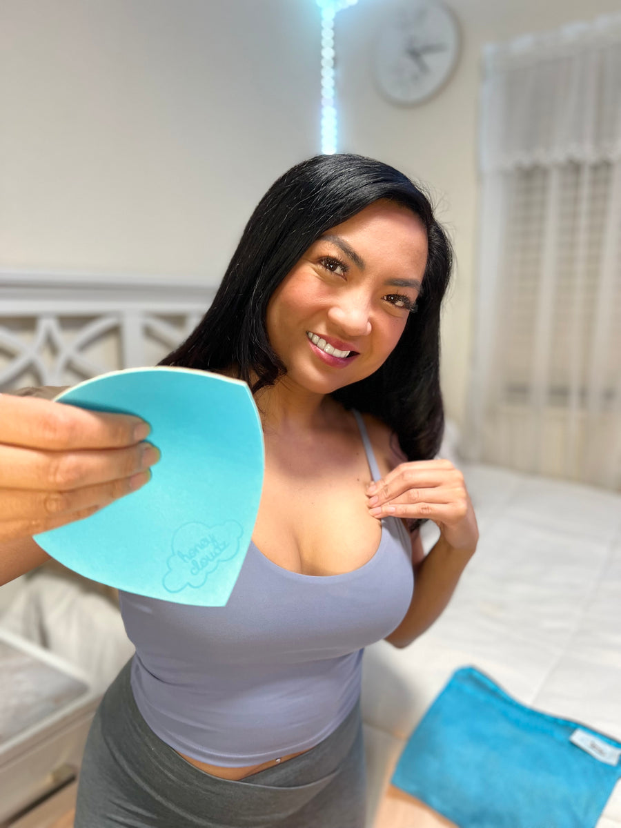 Woman holding a blue Honey Cloudz balancing insert beside her bra