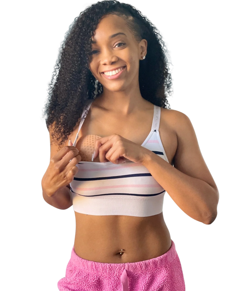 Athletic woman in striped sports bra smiling and holding a beige bra insert, showcasing everyday comfort and versatility