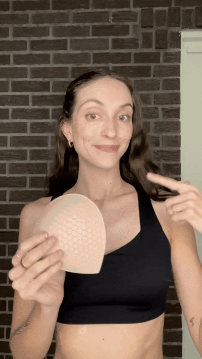 Woman inserting a blue Honeycloudz bra pad into her black sports bra