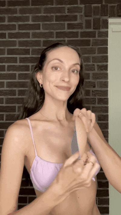 Woman inserting a blue Honeycloudz bra pad into her black sports bra