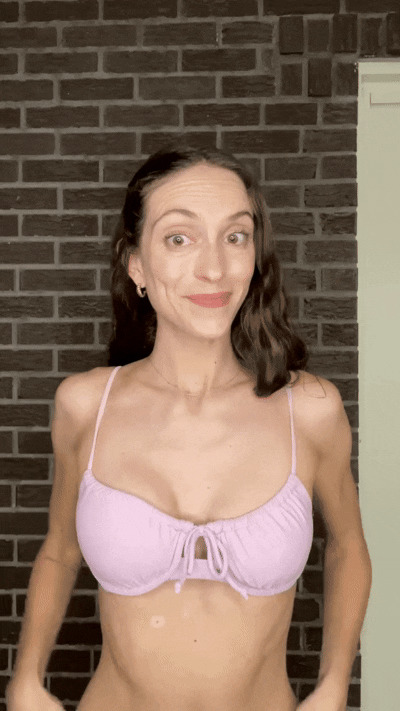 Woman smiling while wearing a black sports bra with Honeycloudz bra pads inserted.