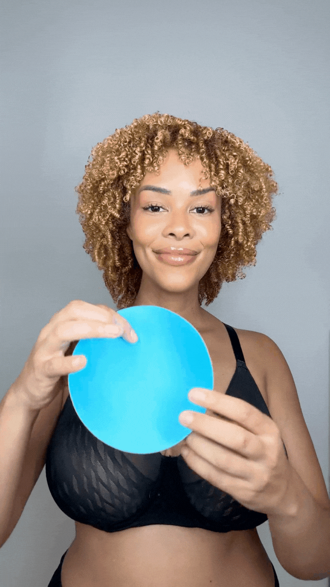 Woman holding a blue Honeycloudz bra pad insert before placing it into a sports bra.