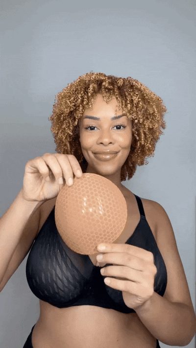 Woman inserting a blue Honeycloudz bra pad into her black sports bra