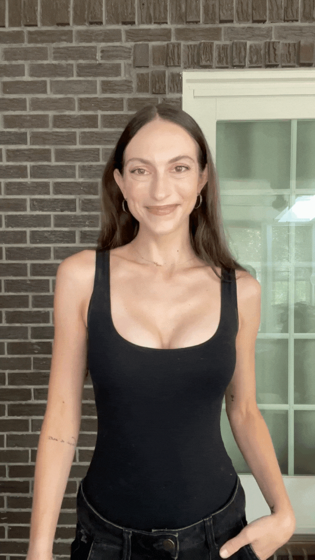 Woman smiling while wearing a black sports bra with Honeycloudz bra pads inserted.