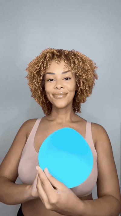 Woman inserting a blue Honeycloudz bra pad into her black sports bra