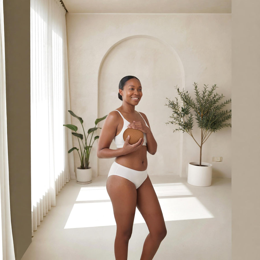 Woman holding a Honey Cloudz breast form over a white bra