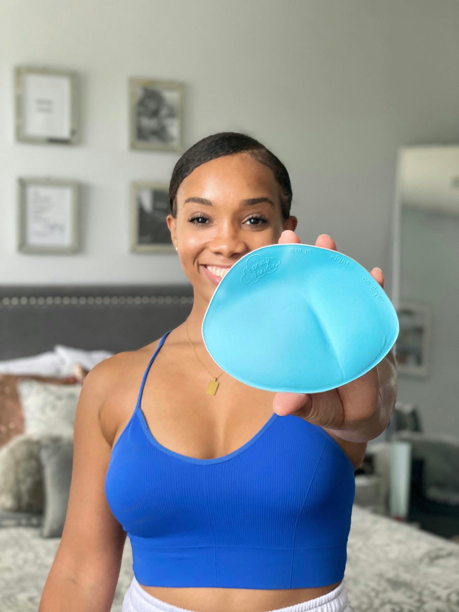 Woman holding a blue Honey Cloudz bra insert while wearing a blue bra